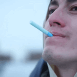 Person using Cigtrus smokeless nicotine-free aroma inhaler outdoors in winter attire.